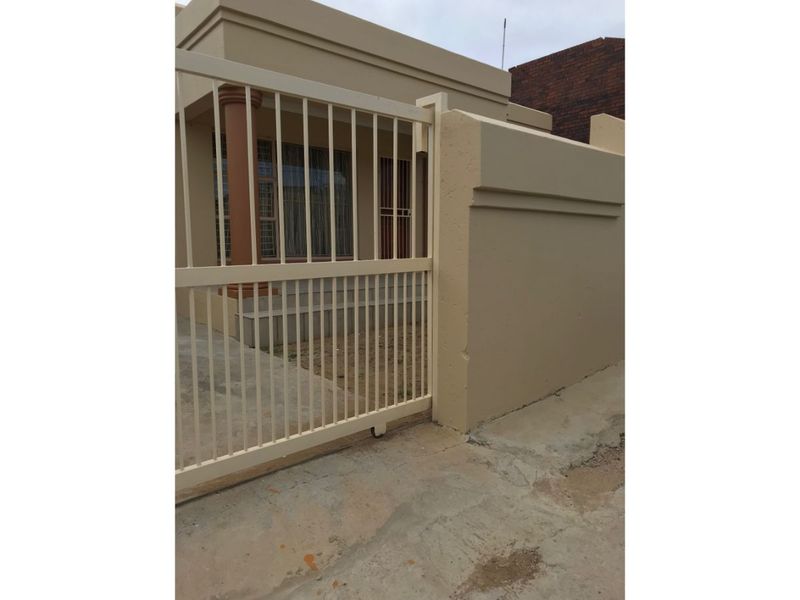 Front exterior view of the property featuring a sliding gate, boundary wall, and concrete driveway access.