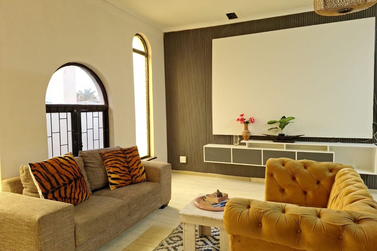 A living room featuring arched windows with security bars, a modern slatted feature wall, and a wall-mounted media console.