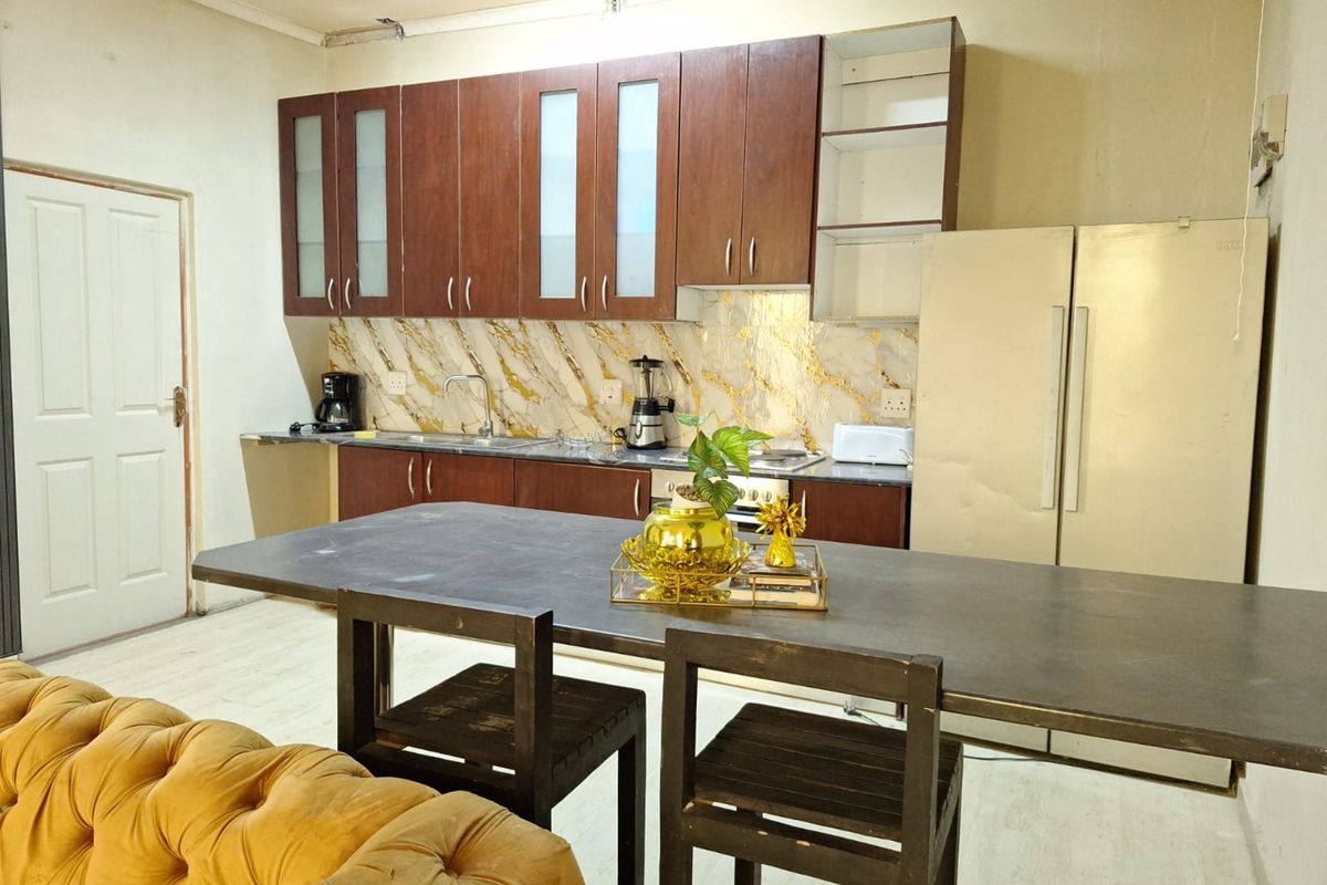 Open plan kitchen area featuring dark wood cabinetry, marble-effect splashback, and integrated sink, requiring minor repairs and cosmetic updates.
