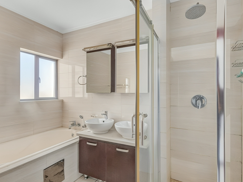 Modern bathroom featuring a dual vessel sink vanity, a separate bathtub, and a glass-enclosed shower with a rain shower head.