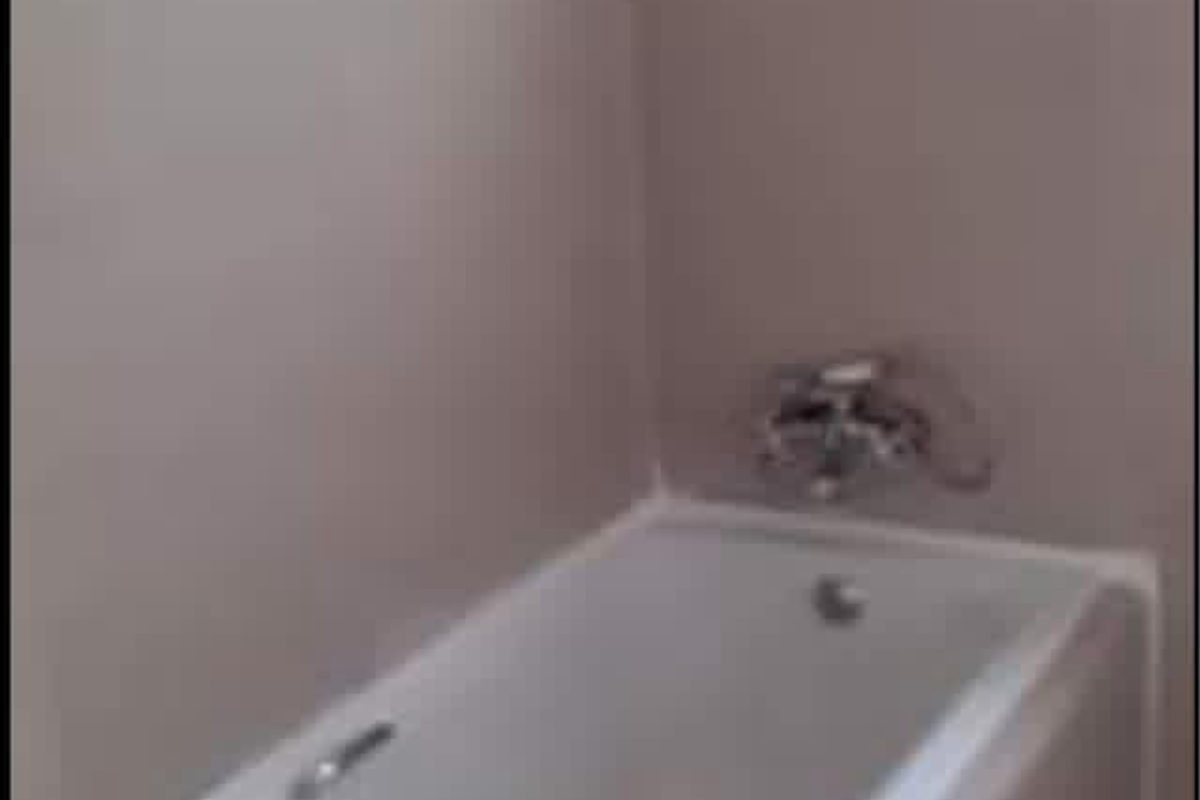 A clean, modern bathroom featuring a built-in bathtub with chrome fixtures and neutral wall tiling.