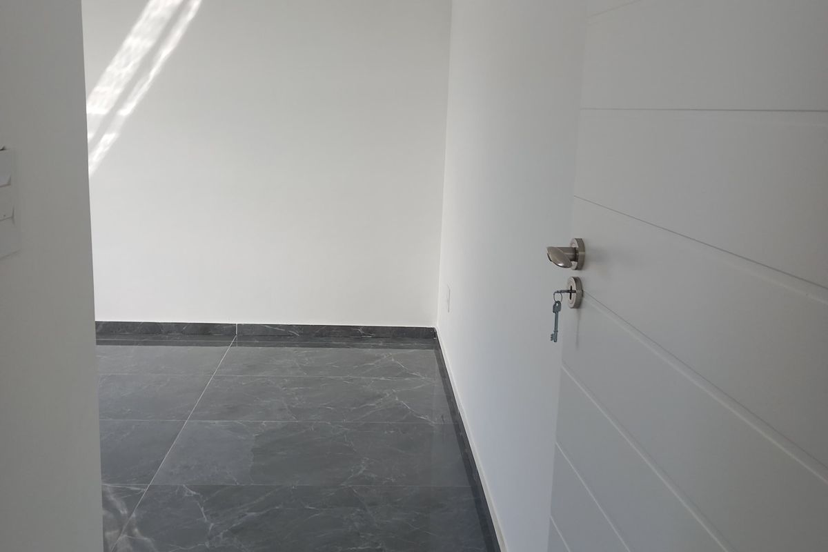 A bright, empty bedroom featuring modern dark marble-effect floor tiles, crisp white walls, and a clean, minimalist aesthetic.