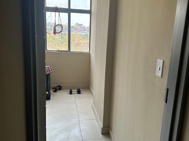 A small, empty utility space or sunroom featuring tiled flooring and a large window with natural light, suitable for a home office or storage.