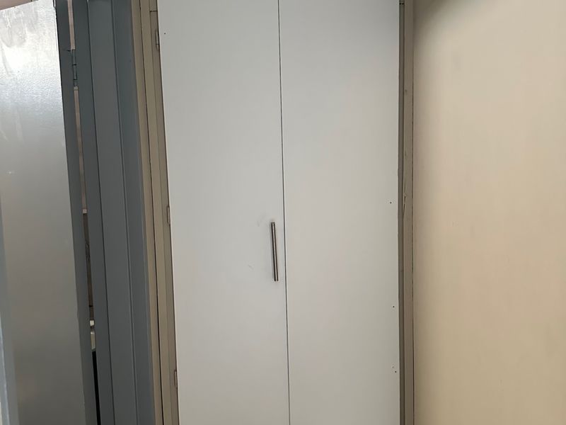 A hallway featuring a white built-in storage cupboard with modern handles.