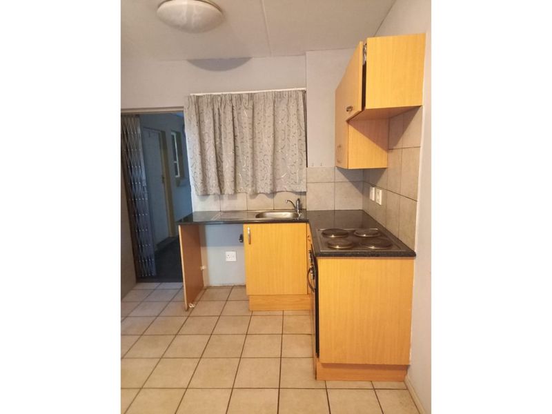 Compact kitchen featuring laminate cabinetry, built-in oven, electric hob, and tiled flooring. The space requires minor repairs to cabinetry.