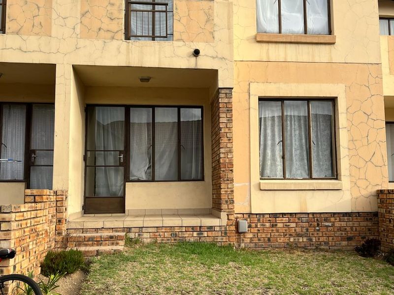 Front elevation of a two-story flat featuring brick accents, a small patio area, and balcony access with visible exterior plaster cracking.