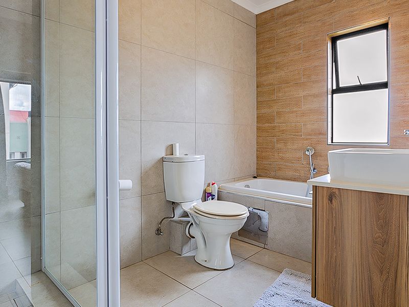 Modern bathroom featuring a glass shower enclosure, bathtub, vanity with vessel sink, and contemporary neutral wall and floor tiling.
