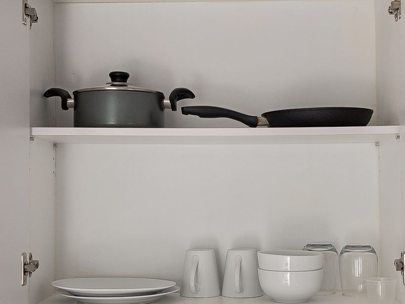 A close-up view of clean, white kitchen cabinetry featuring organized shelving for storage.