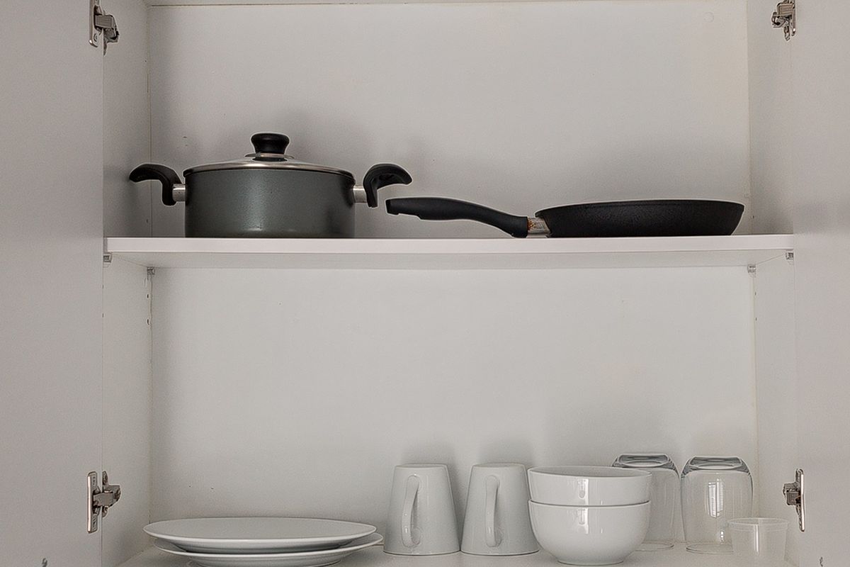 A close-up view of clean, white kitchen cabinetry featuring organized shelving for storage.