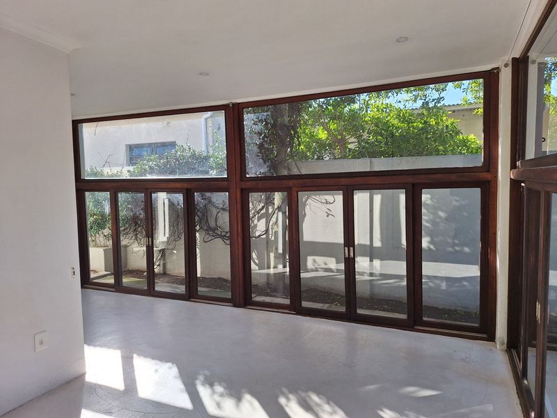 Bright and spacious living area featuring polished concrete floors and expansive timber-framed folding glass doors that open to the garden.