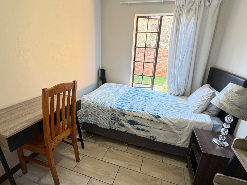 A functional bedroom featuring tiled flooring and a glass-paned french door providing direct access to the outdoor area.