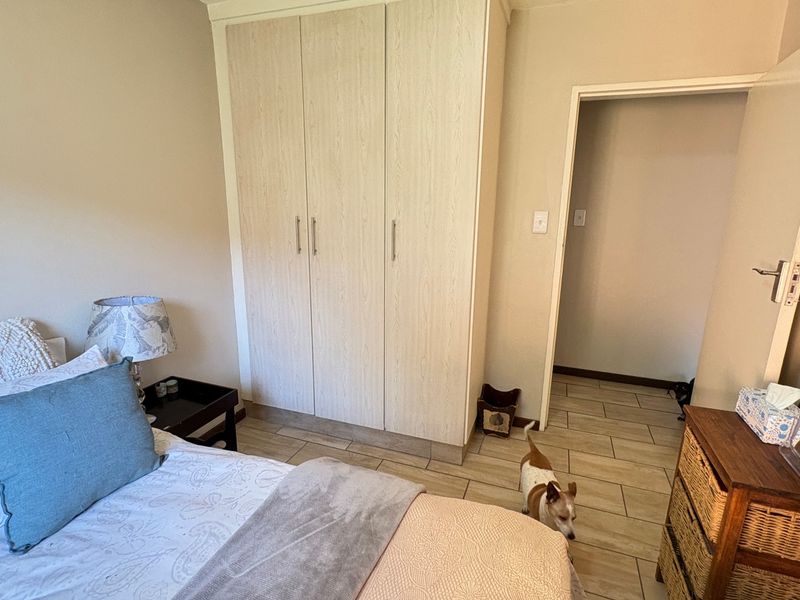 A bedroom featuring light-toned built-in wardrobes and neutral tiled flooring, providing a clean and functional living space.