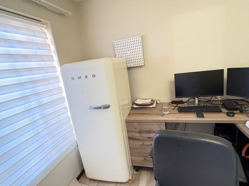A functional home office space featuring neutral walls and modern roller blinds, providing a practical area for work or study.