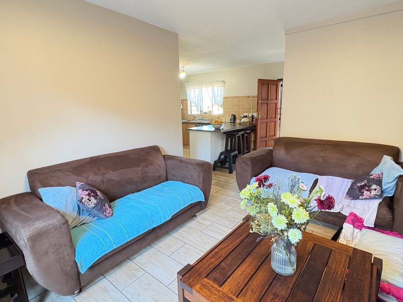 Open plan living area featuring tiled flooring with a view through to the kitchen space.