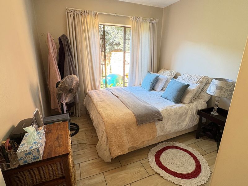 A cozy bedroom featuring tiled flooring and a sliding glass door that provides natural light and access to the exterior.