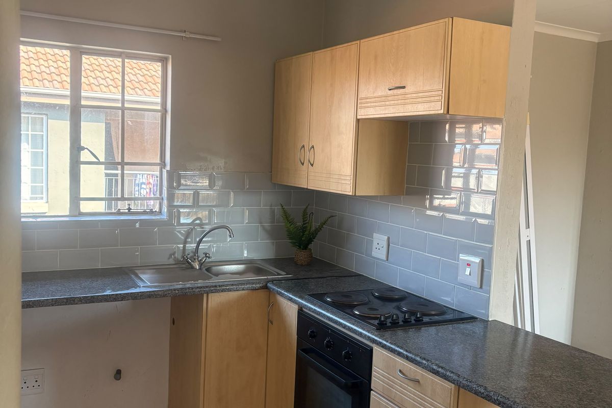 A functional kitchen featuring light wood cabinetry, granite-look countertops, subway tile backsplash, and integrated electric cooking appliances.