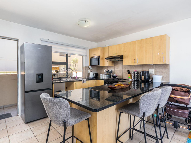 Functional kitchen featuring granite countertops, a central island, and light wood cabinetry, with direct access to an outdoor balcony area.