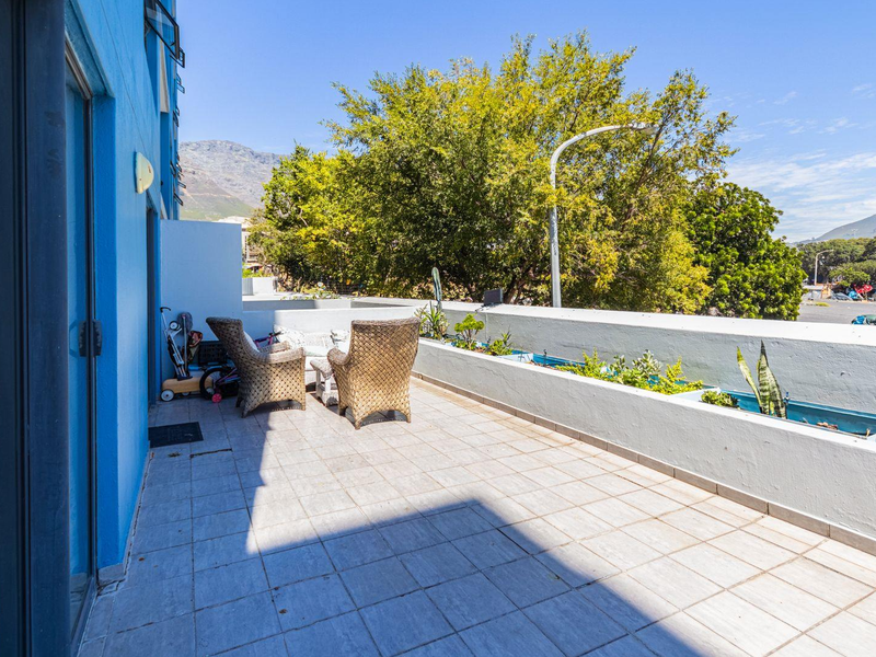 Spacious balcony featuring tiled flooring and built-in planter boxes, offering an outdoor living area with views of the surrounding trees and mountains.