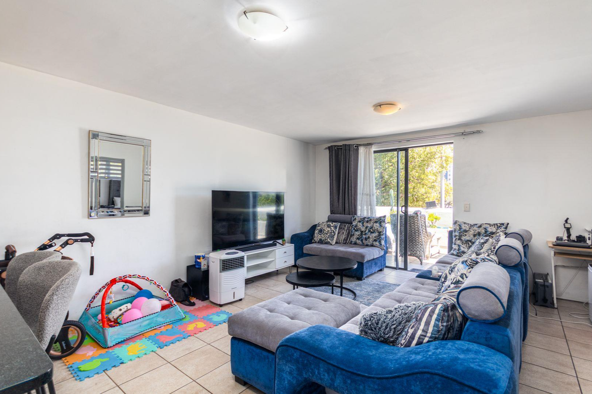 A spacious living room featuring tiled flooring and a large sliding glass door that provides access to an outdoor area.
