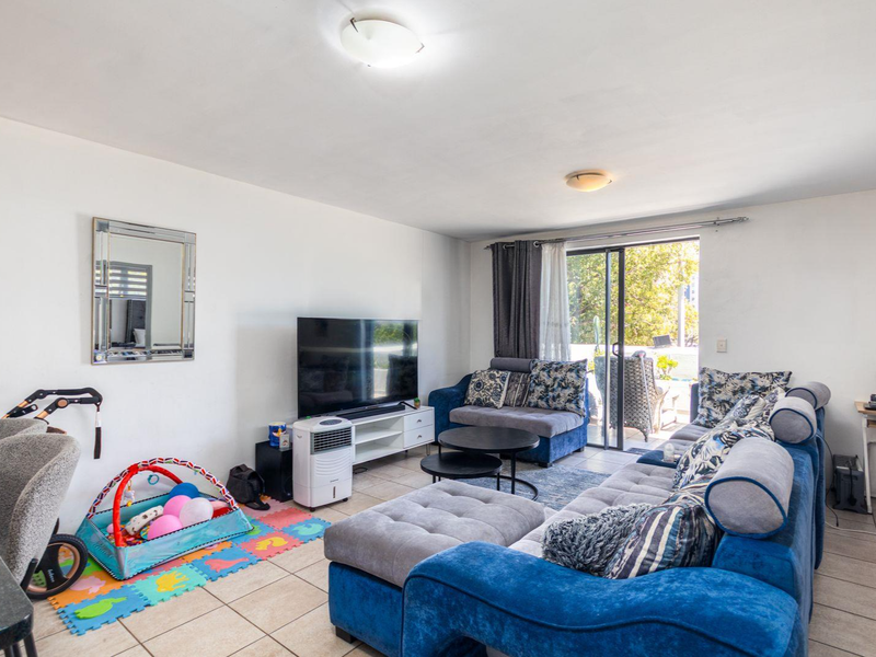 A spacious living room featuring tiled flooring and a large sliding glass door that provides access to an outdoor area.