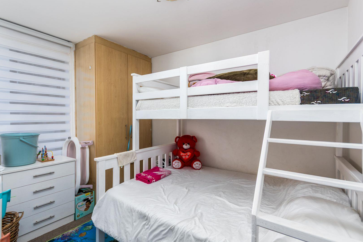A functional bedroom featuring a built-in wardrobe and a window fitted with a modern roller blind.