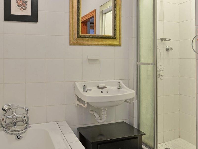 A functional bathroom featuring a built-in bathtub, a separate shower enclosure, and a wall-mounted basin with tiled wall finishes.