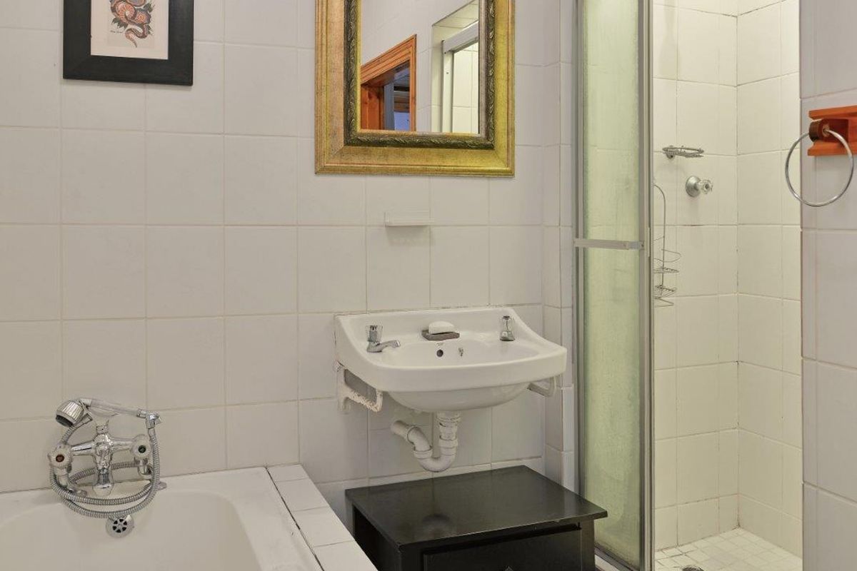 A functional bathroom featuring a built-in bathtub, a separate shower enclosure, and a wall-mounted basin with tiled wall finishes.