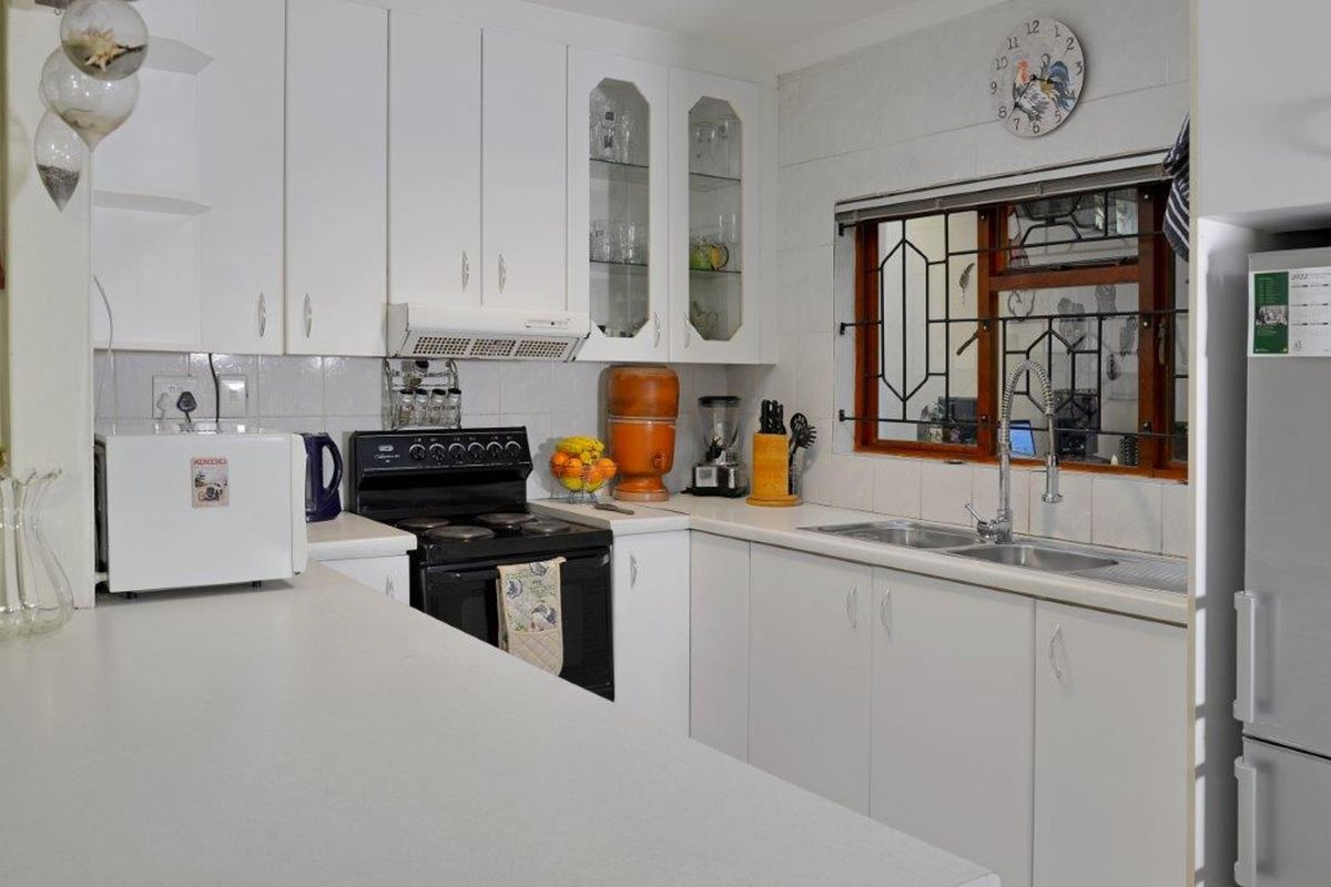 A functional kitchen featuring white cabinetry, laminate countertops, a double basin sink, and a tiled backsplash with a window overlooking the exterior.