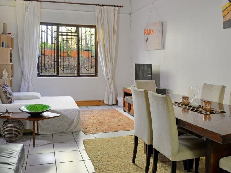 Open plan living and dining area featuring tiled flooring and a window with security bars.