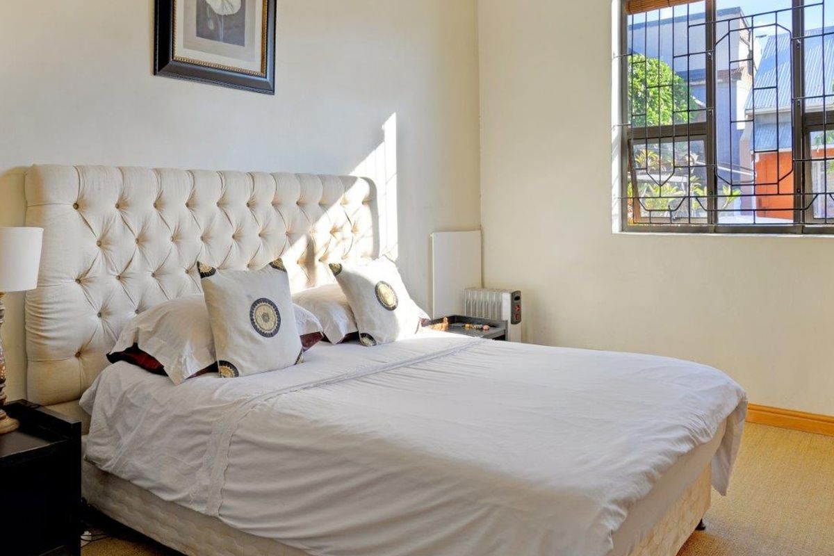 A well-lit bedroom featuring a large window with security burglar bars and neutral wall finishes.