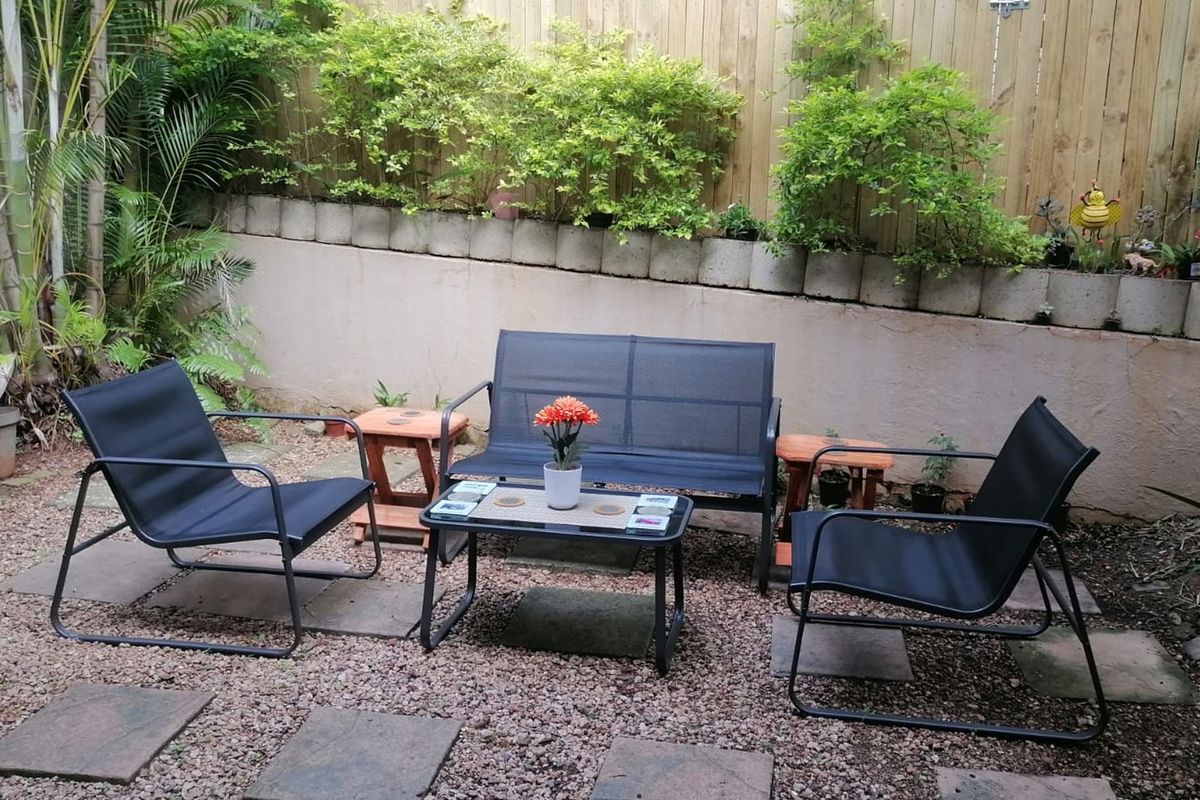 A private rear courtyard featuring a gravel base, stone pavers, and a timber boundary fence with a low retaining wall.