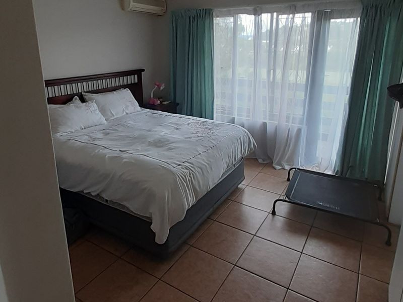 A bedroom featuring tiled flooring, a wall-mounted air conditioning unit, and a sliding glass door providing access to an outdoor area.