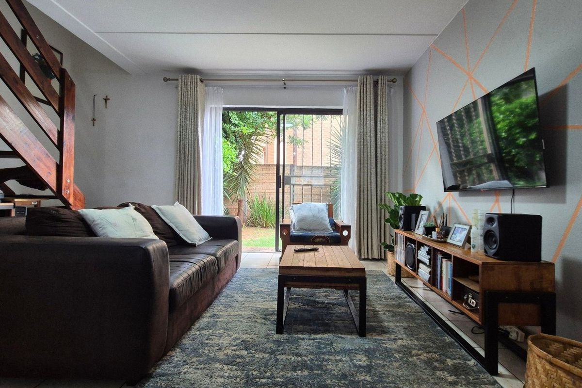 A comfortable living room featuring a wooden staircase, tiled flooring, and a sliding glass door providing direct access to the outdoor area.