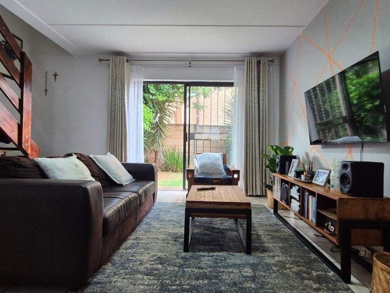 A comfortable living room featuring a wooden staircase, tiled flooring, and a sliding glass door providing direct access to the outdoor area.