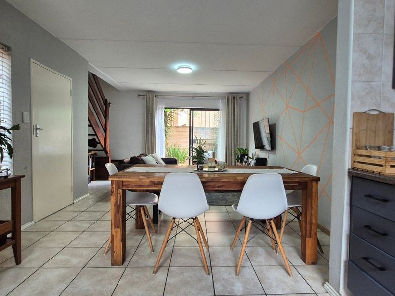 Open-plan living and dining area featuring tiled flooring, a staircase, and direct access to an outdoor space through sliding glass doors.