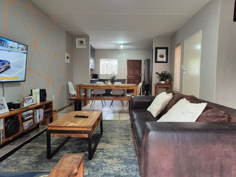 An open-plan living and dining area featuring tiled floors, a staircase, and a connected kitchen space with neutral wall finishes.