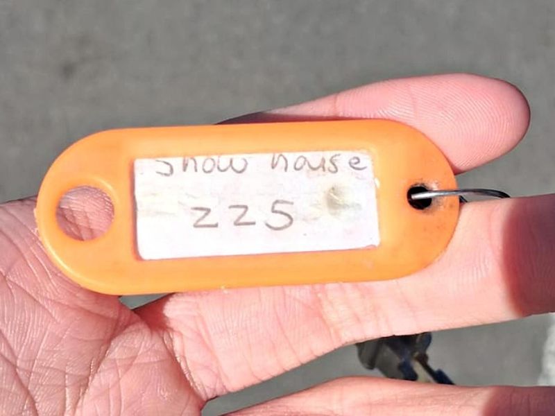 A close-up photograph of a hand holding a plastic key tag labeled with text.