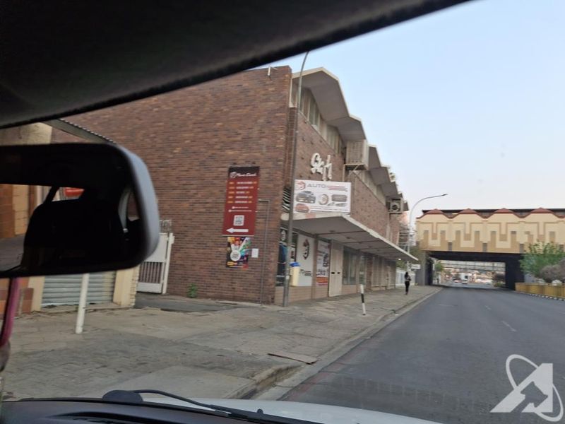 Street-level view of a commercial brick building with signage, captured from a vehicle.