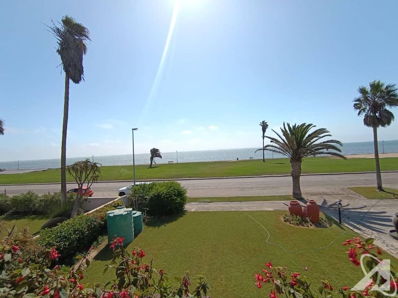 A scenic elevated view overlooking a manicured garden, coastal road, and the ocean beyond.