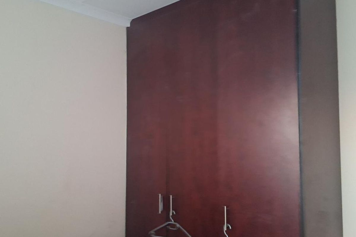 A bedroom featuring a dark wood built-in wardrobe with clean lines and simple coving detail.