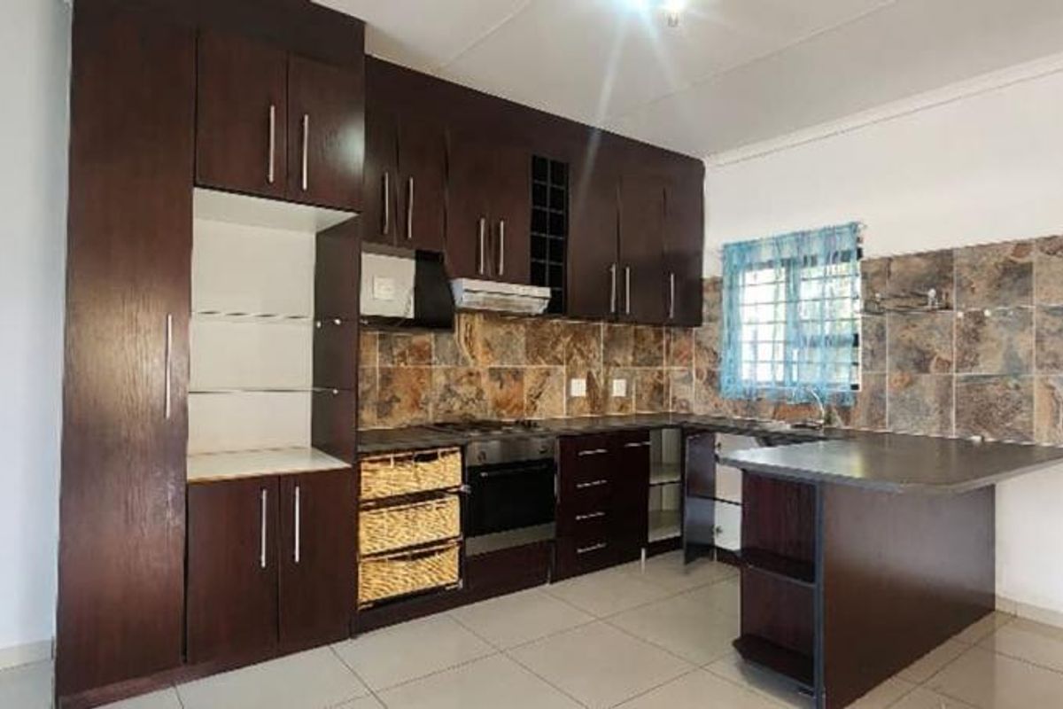 Kitchen featuring dark wood cabinetry, stone-look tile backsplash, built-in oven, extractor fan, and a breakfast bar peninsula.