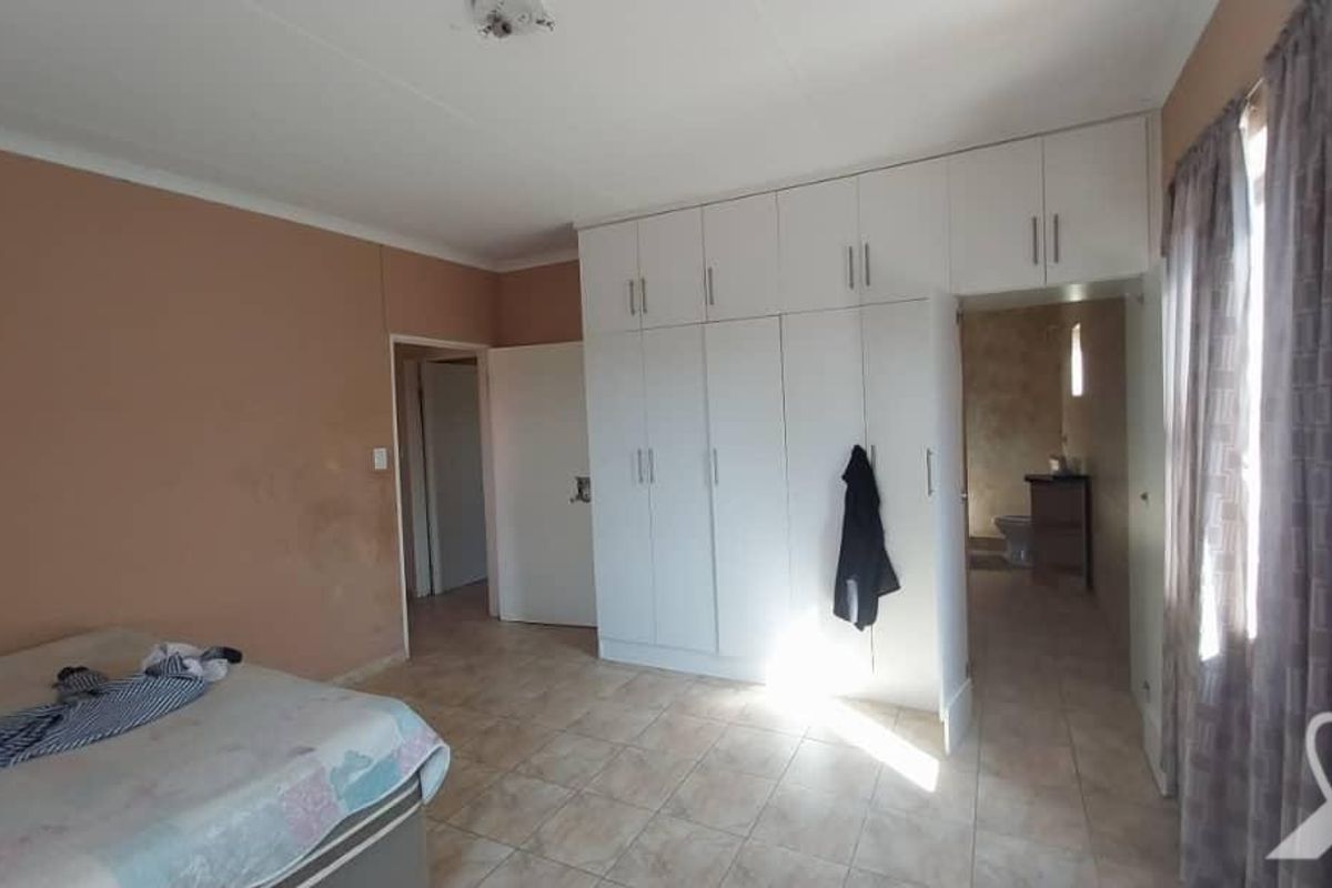 Bedroom featuring built-in floor-to-ceiling cabinetry, tiled flooring, and an en-suite bathroom access.