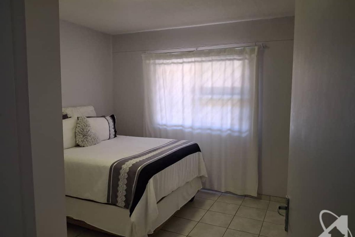 A bedroom featuring tiled flooring and a window with curtain tracks.