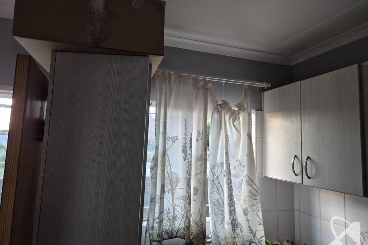 A dated kitchen area featuring built-in cabinetry and tiled splashbacks, requiring cosmetic updates to modernize the space.