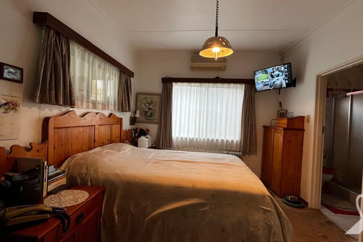 A bedroom featuring a wall-mounted air conditioning unit, pendant lighting, and an en-suite bathroom access.