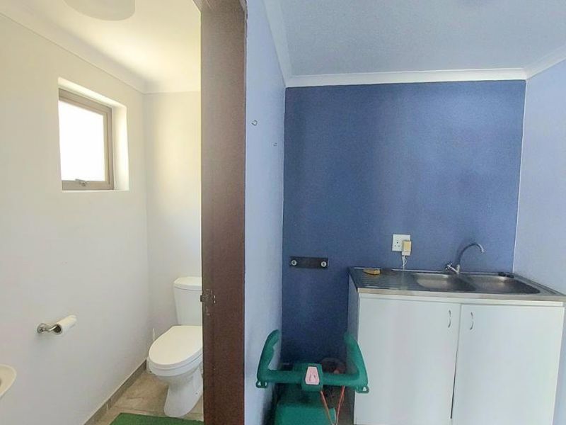 A functional laundry area featuring a built-in sink and cabinetry, with an adjacent separate toilet room.