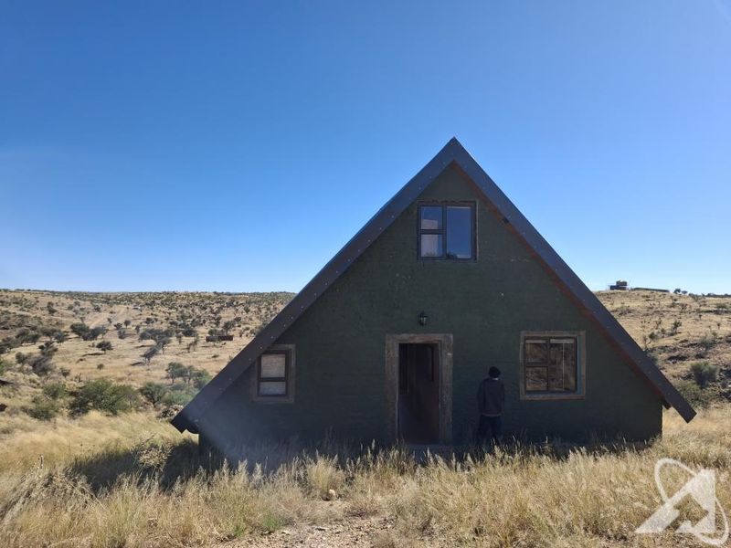 A rustic A-frame dwelling situated in a rural landscape, featuring a pitched roof and simple exterior facade.