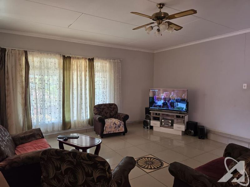 Spacious living room featuring tiled flooring, a ceiling fan, and large windows allowing for natural light.