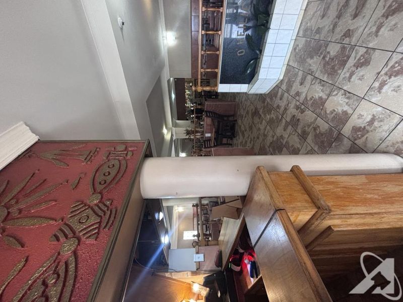 Commercial entry area featuring a reception desk, tiled flooring, and decorative wall elements, presenting a dated aesthetic suitable for modernization.