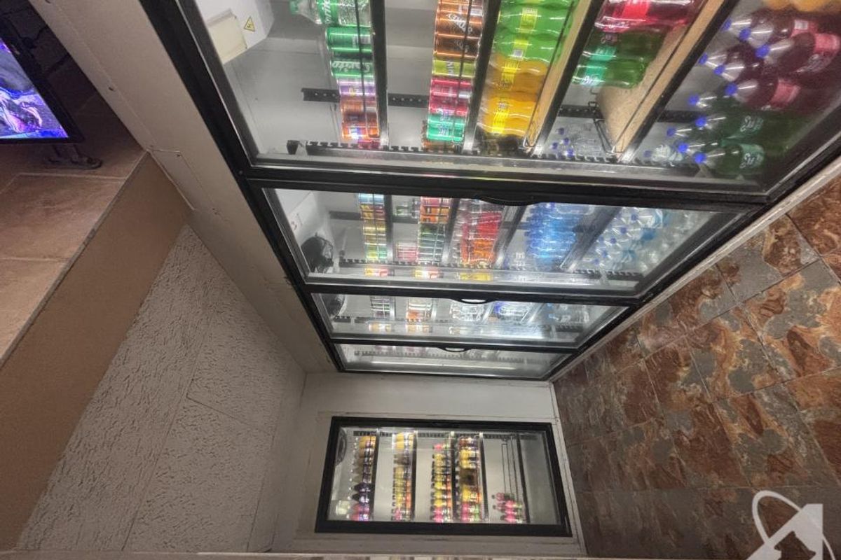 Commercial utility area featuring multiple built-in glass-fronted refrigeration units for beverage storage and durable tiled flooring.